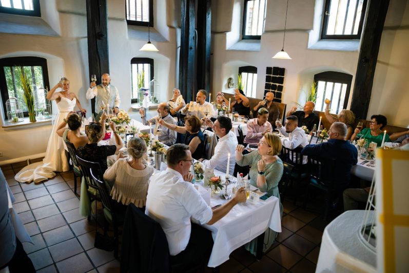 Sektglas wird hochgehoben von den Hochzeitsgästen Hochzeitsgäste heben Sektglas hoch und stoßen an