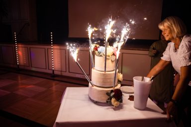 Eine mehrstöckige Torte mit Funken, eine Person daneben, die sie betrachtet.