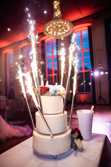 Dreistöckiger Hochzeitstorte mit Funken und Blumenverzierung, festliche Atmosphäre.