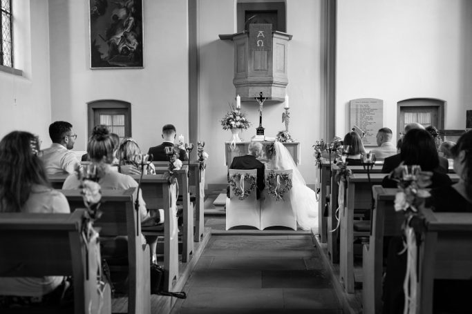 Hochzeit Karlsruhe – Brautpaar sitzt bei der Trauung von hinten aufgenommen Brautpaar sitzt bei der Trauung in Karlsruhe