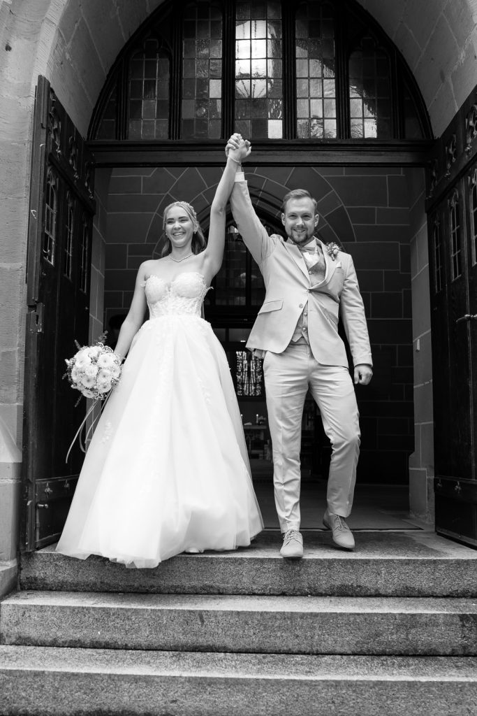 Hochzeit Stuttgart – Brautpaar läuft nach der kirchlichen Trauung aus der Kirche Brautpaar läuft nach der Trauung strahlend aus der Kirche in Stuttgart – emotionaler Auszug, Hochzeitsgäste jubeln, unvergesslicher Hochzeit