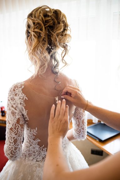 Brautjungfer hilft Braut beim Anziehen des Kleids bei Hochzeit in Stuttgart