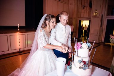 Brautpaar beim Tortenanschnitt in Heilbronn – lachend, verschmitzt, gemeinsamer Anschnitt der Hochzeitstorte, fröhlicher Moment