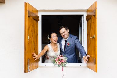 Brautpaar schaut lustig aus einem Weinberghaus bei Hochzeit in Stuttgart.