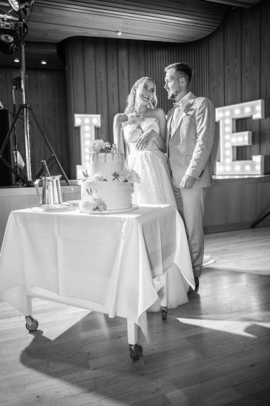 Brautpaar schneidet Hochzeitstorte an bei Feier in Karlsruhe – traditioneller Tortenanschnitt, lachende Gäste, festlicher Moment bei der Hoc