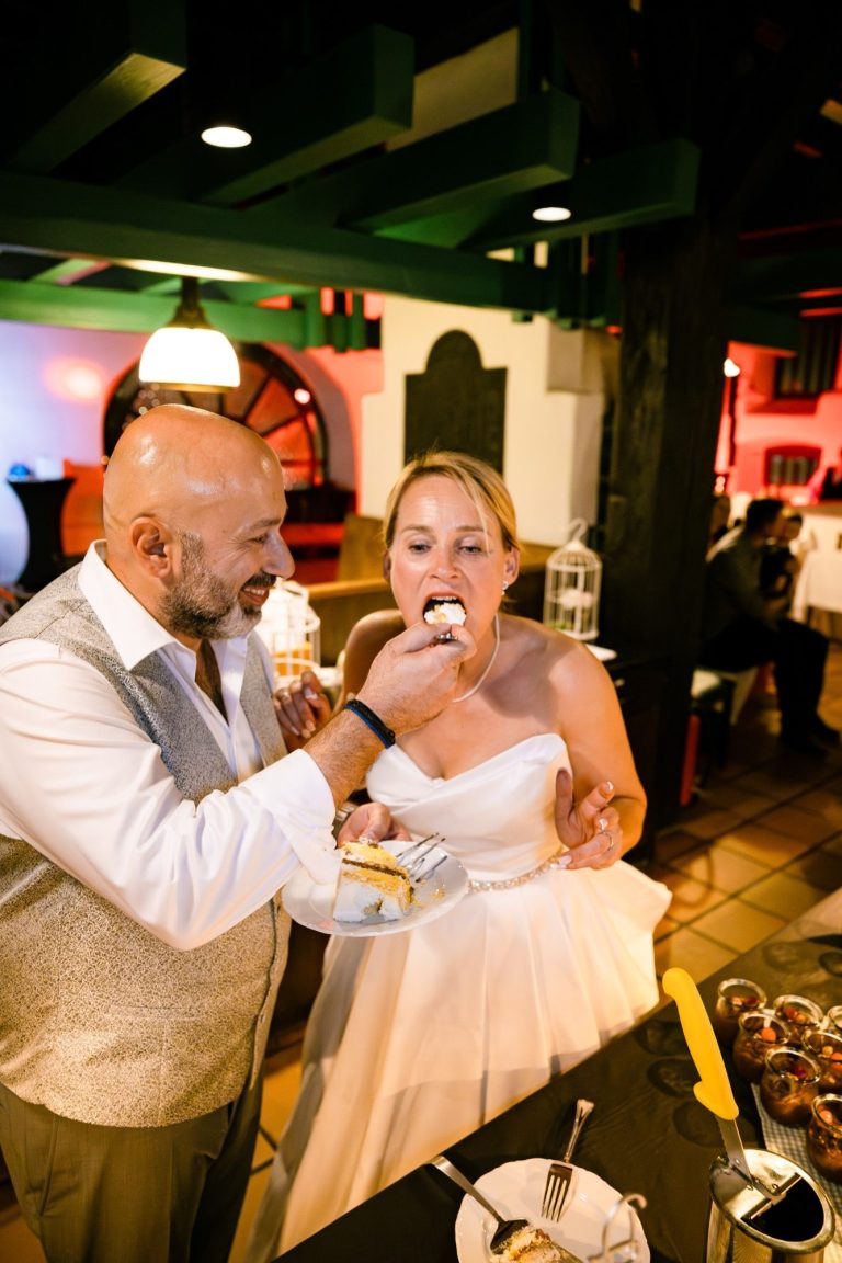 Essen einer Hochzeitstorte Braut probiert die Hochzeitstorte und der Bräutigam hilft der Braut