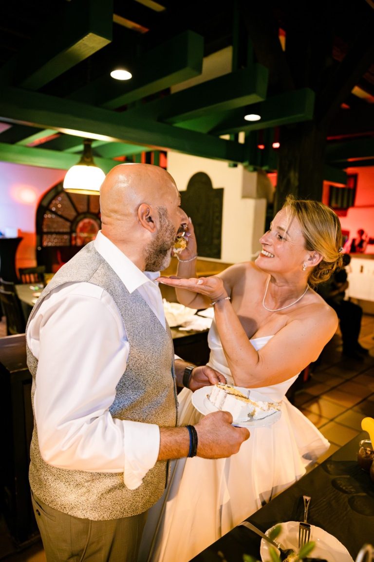 Der Bräutigam isst die Hochzeitstorte Bräutigam probiert die Hochzeitstorte und die Braut hilft dem Bräutigam