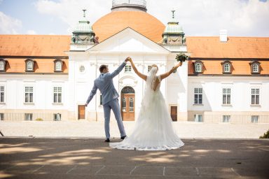 Fröhliches Brautpaar hebt bei Fotoshooting in Stuttgart die Arme hoch – ausgelassenes Hochzeitsfoto, Paar zeigt Freude und Leichtigkeit.